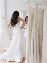 Mixed race woman trying on wedding dresses