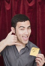 Mixed race man holding Call Me sticky note and gesturing