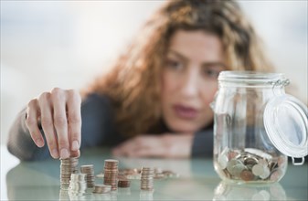Hispanic woman counting coins from jar