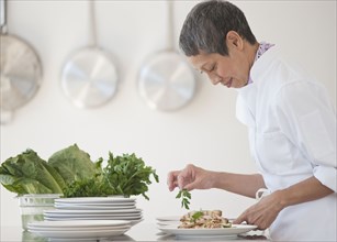 Chinese chef plating meals in professional kitchen