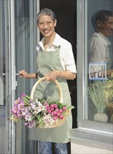 Chinese florist holding basket of flowers in doorway