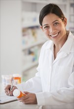 Hispanic pharmacist holding prescription bottle