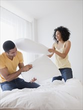 Couple pillow fighting on bed