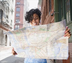 Mixed race woman holding map on urban street