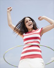 Mixed race woman spinning plastic hoop