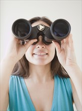 Mixed race woman looking through binoculars