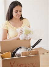 Mixed race woman packing moving box