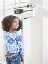 Mixed race girl being weighed at doctor's office