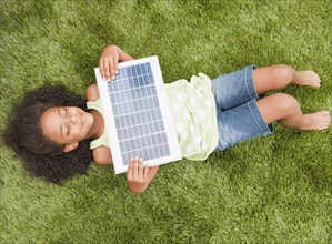 Mixed race girl laying with solar panel