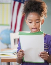 Mixed race girl reading report at school