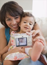 Hispanic mother taking self-portrait with daughter