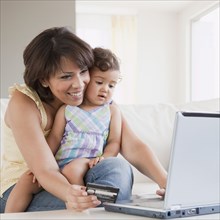 Hispanic mother and daughter looking at laptop