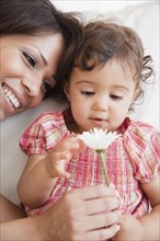 Hispanic mother and daughter looking at flower