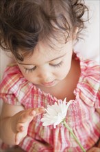 Hispanic baby girl looking at flower