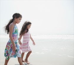 Hispanic sisters walking on beach