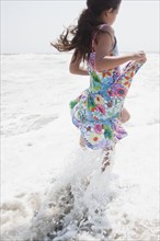 Hispanic girl wading on ocean