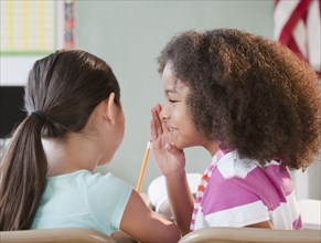School girl whispering to friend
