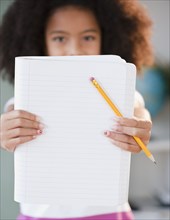 Hispanic girl holding out notebook