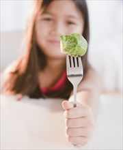 Mixed race girl holding brussels sprout