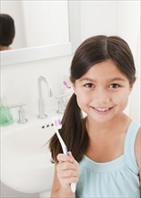 Mixed race girl holding toothbrush