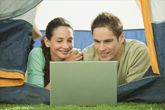 Hispanic couple using laptop in tent