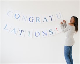 Mixed race woman putting up congratulations sign