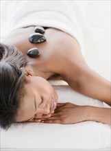 Mixed race woman having hot stone therapy