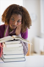 Mixed race woman looking at stack of books