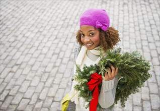 Mixed race woman carrying Christmas wreath