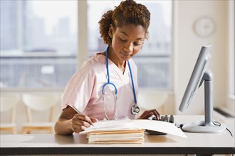 Mixed race nurse working on medical charts at computer