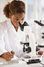 Mixed race scientist peering into microscope