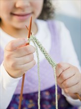 Hispanic girl knitting with yarn