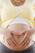 Pregnant Hispanic woman holding bare stomach