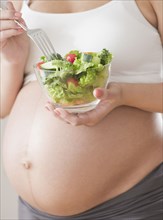 Pregnant Hispanic woman eating salad