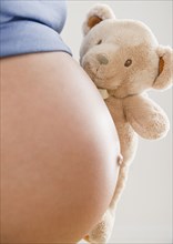 Pregnant Hispanic woman holding teddy bear