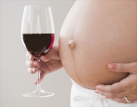 Pregnant Hispanic woman holding glass of wine