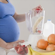 Pregnant Hispanic woman making fruit smoothie