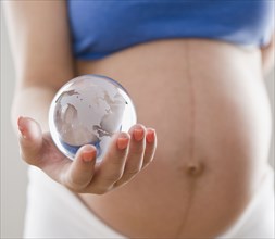 Pregnant Hispanic woman holding glass globe