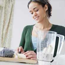 Mixed race woman preparing smoothie