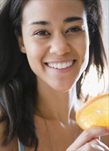 Mixed race woman holding orange slice