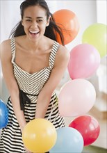 Laughing mixed race woman with balloons
