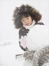 Chinese girl building snowman