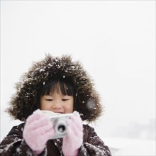 Chinese girl in snow using digital camera