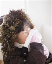 Chinese girl in coat blowing nose