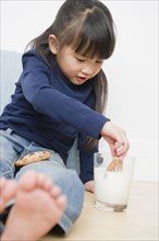 Chinese girl dunking cookies in milk