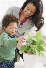 Mixed race mother helping son water plants