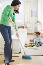 Mixed race mother sweeping floor