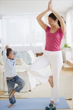 Mixed race mother and son practicing yoga