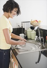Hispanic woman washing pan in kitchen