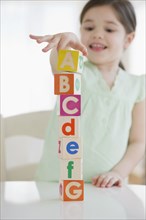 Mixed race girl stacking alphabet blocks